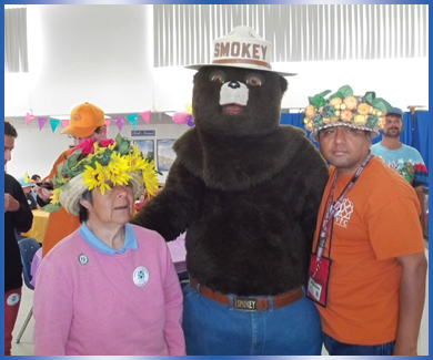 VTC individuals in party hats posing with Smokey the Bear at annual Spring Fling event